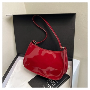 Close-up of a red patent leather shoulder bag in a black gift box with dust bag