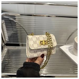 Detail of mini crossbody bag featuring purple M-pattern print and golden chain strap