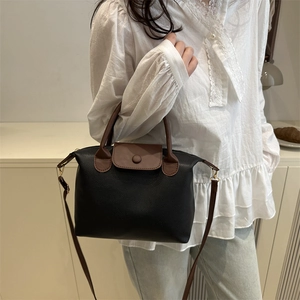 Women's minimalist black and brown contrast pillow bag with top handle and shoulder strap