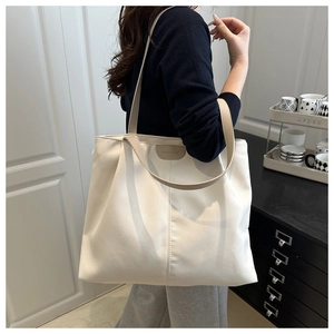 Détail d'un grand sac cabas blanc avec anses marron et écusson en cuir embossé mode