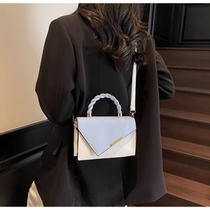 Modern light blue and white square shoulder bag styled with a woven handle and black blazer