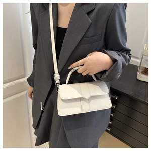 Detail showing white geometric crossbody bag with fine leather texture and adjustable strap