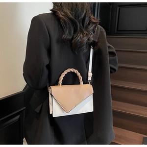 Detail of trendy small square bag showing woven handle and chic white beige contrast design
