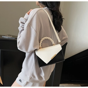 Detailed side view of chic black and white flap bag with twisted handle and gold clasp