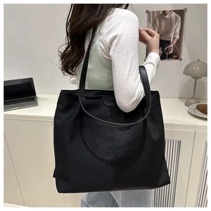 Détail du grand sac cabas noir avec sangle en cuir dans un bureau au style moderne