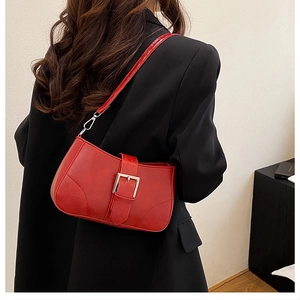 Detail of red leather shoulder bag with silver metal buckle on a shoulder model