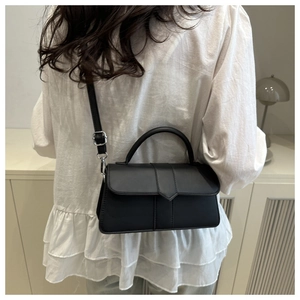 Rear view of model wearing a minimalist black leather crossbody bag with silver hardware