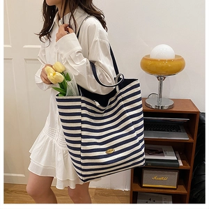 Detail of blue and white striped canvas tote bag with black strap and vintage logo patch