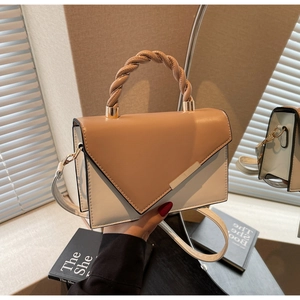 Detail of twisted handle and metal bar decoration on khaki and beige flap shoulder bag