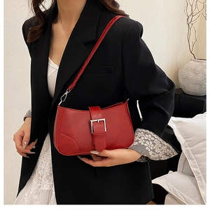 Detail of red leather bag with silver buckle worn by a model in a black blazer