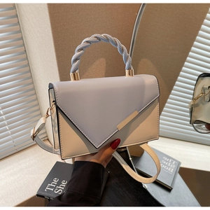 Detail of blue woven handle and cream flap on a chic two-tone square crossbody bag