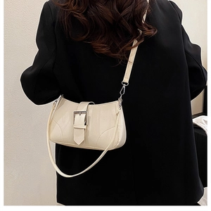 Chic cream small square bag with decorative buckle and curved stitching shown on model