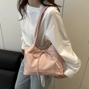 Pink PU leather tote bag with bow detail worn as a stylish shoulder bag in modern interior