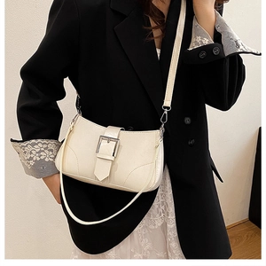 Detail shot of a cream leather crossbody bag featuring a sleek silver metal buckle