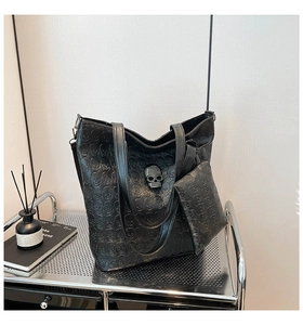 Detail of black punk tote bag featuring embossed skull texture and studded metal hardware