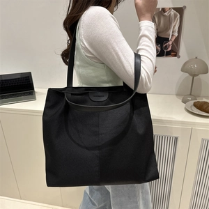 Grand sac fourre-tout noir minimaliste porté à l'épaule par un mannequin pour le quotidien