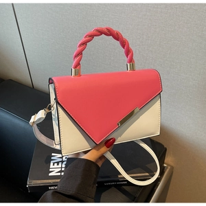 Detail of pink and white crossbody bag featuring a twisted handle and gold buckle