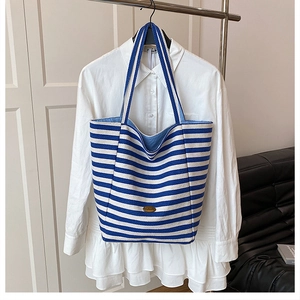 Detail of blue and white striped canvas tote with handmade metal tag and inner lining