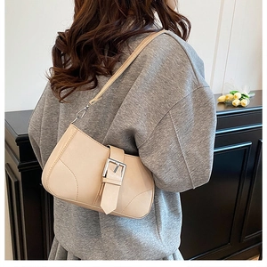 Close-up of cream leather shoulder bag with wide strap and silver buckle detail