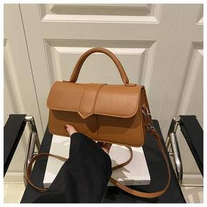 Detailed close-up of a caramel faux leather rectangular handbag with a rounded top handle