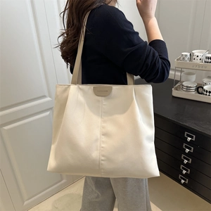 Grand sac cabas minimaliste crème porté par un mannequin dans un décor moderne