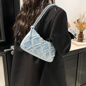 Chic light blue denim crescent shoulder bag with fringe texture and knotted strap detail