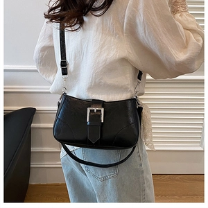 Detail of a black glossy crossbody bag with silver buckle and slim shoulder strap