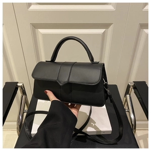 Detail of minimalist black matte leather square bag with V-shaped flap and silver hardware