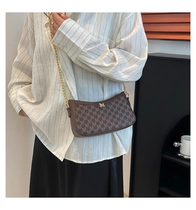 Detail view of a vintage brown handbag with M pattern and golden chain strap for women