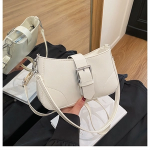 Detail of white leather shoulder bag featuring silver metal buckle and fine stitching