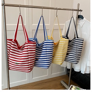 Close-up of textured canvas tote bag featuring horizontal stripes and a vintage leather logo