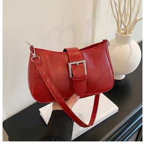 Close-up of the vintage red shoulder bag with a large silver buckle and glossy leather