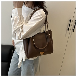 Detail of vintage dark brown leather tote bag with elegant golden triangle logo hardware