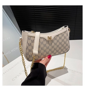 Detail showing beige underarm bag with M monogram pattern and gold chain strap