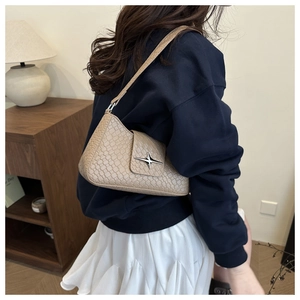 Detail of beige faux crocodile leather shoulder bag with silver star buckle