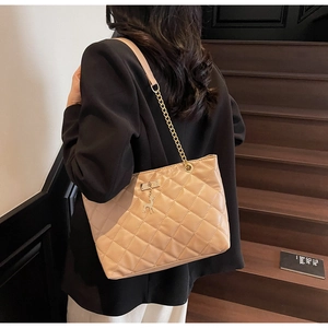 Detail of khaki quilted tote bag featuring golden chain strap and deer charm pendant