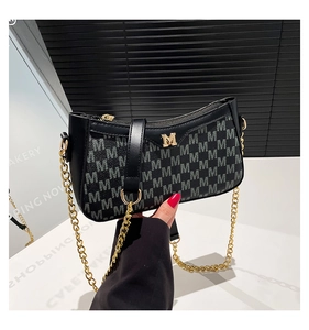 Detail of black underarm bag with gold M hardware and monogram jacquard pattern