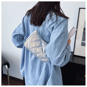 Detailansicht der silbernen Stepptasche mit Kette, getragen von einem Model