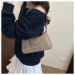 Detail of khaki faux crocodile leather underarm bag with silver star hardware on a model
