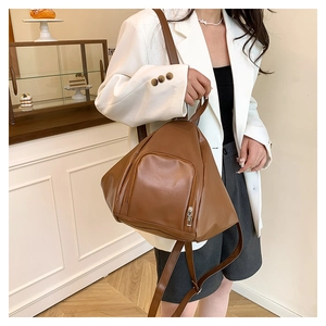 Detail of minimalist dark brown leather backpack showing triangle shape and zipper pocket