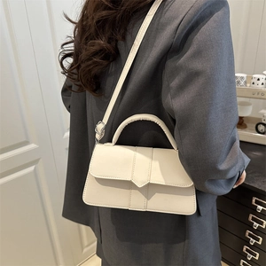 Chic cream white rectangular crossbody bag with geometric clasp shown on a grey blazer