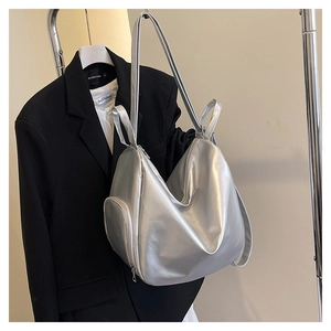 Silver metallic tote bag detail showing luxury texture and side zipper on a clothes rack