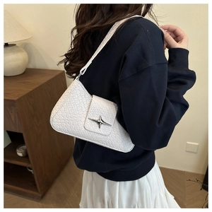 Detail of white crocodile texture underarm bag with star buckle shown on model