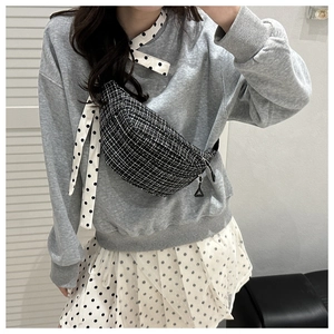 Sac bandoulière en tweed noir et blanc porté par un mannequin avec motif à carreaux