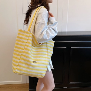 Chic yellow and white striped canvas tote bag with handmade label shown on a model