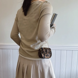 Women's leopard print saddle bag with gold chain strap shown on model back