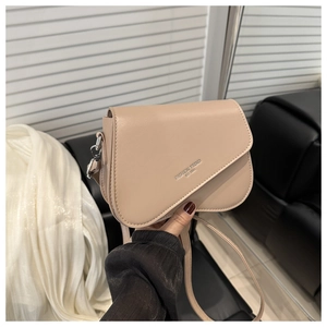 Détail du sac bandoulière beige en similicuir avec rabat asymétrique et logo tendance