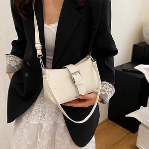Fashionable cream square crossbody bag with silver buckle worn by a model in lifestyle setting