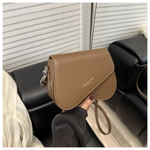 Détail d'un sac bandoulière en cuir mat marron avec lettrage argenté et boucle métal