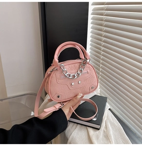 Detail of pink croc-embossed shell bag featuring silver hardware studs and chain strap
